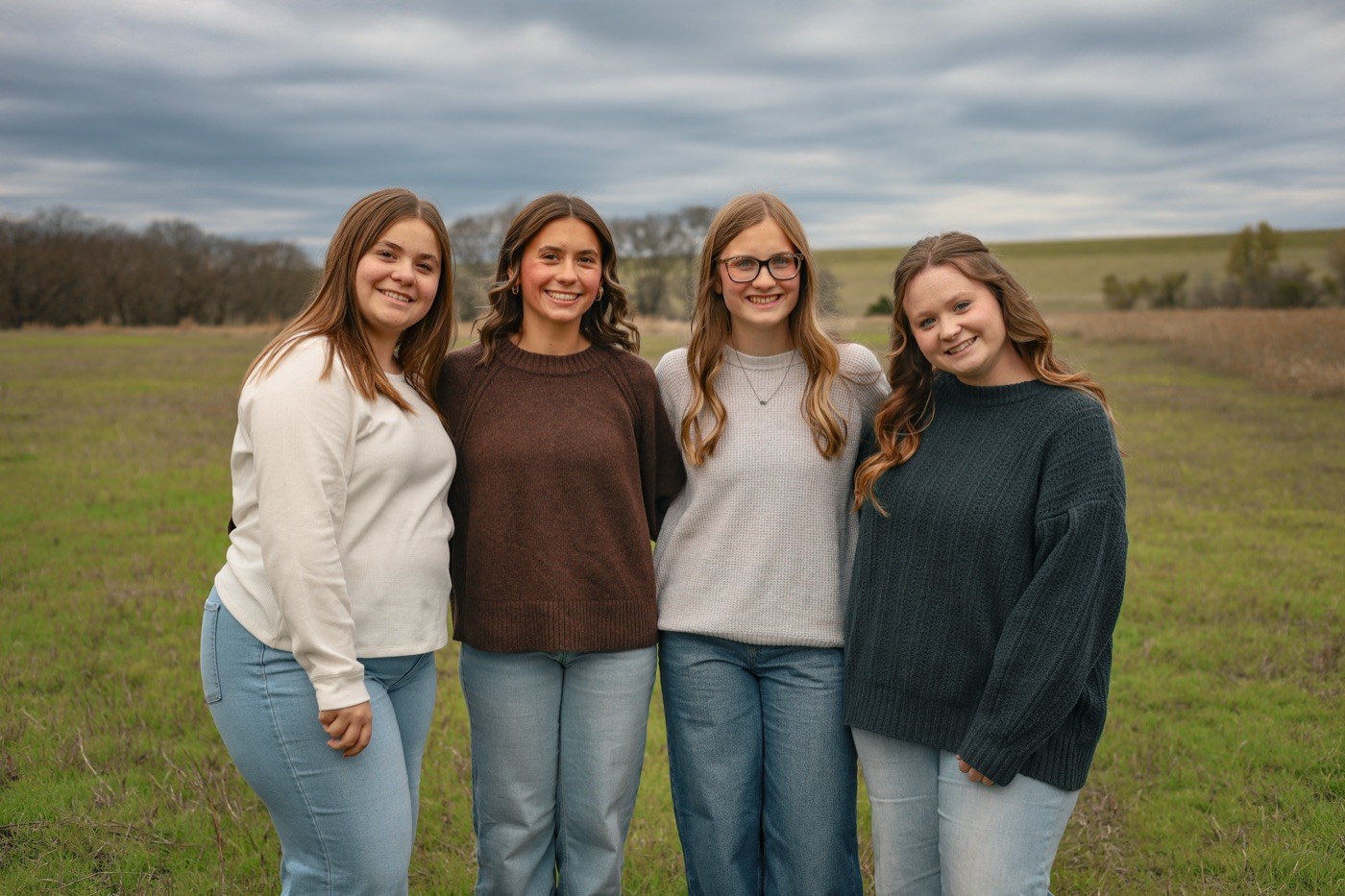 Four friends standing shoulder to shoulder in a winter field.