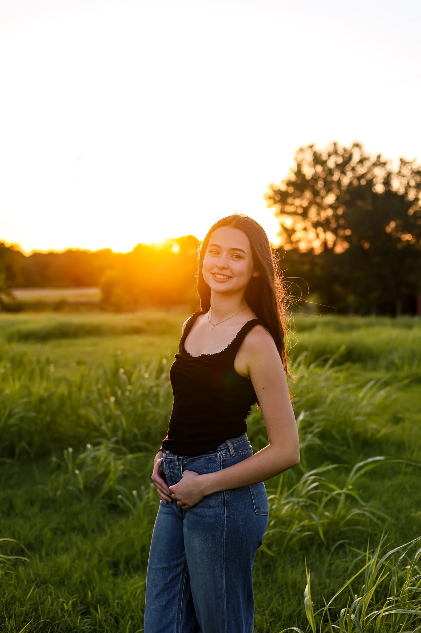 A senior standing in a field at sunset.